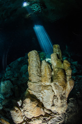 Rayons de lumière sur stalagmite dans un cenote